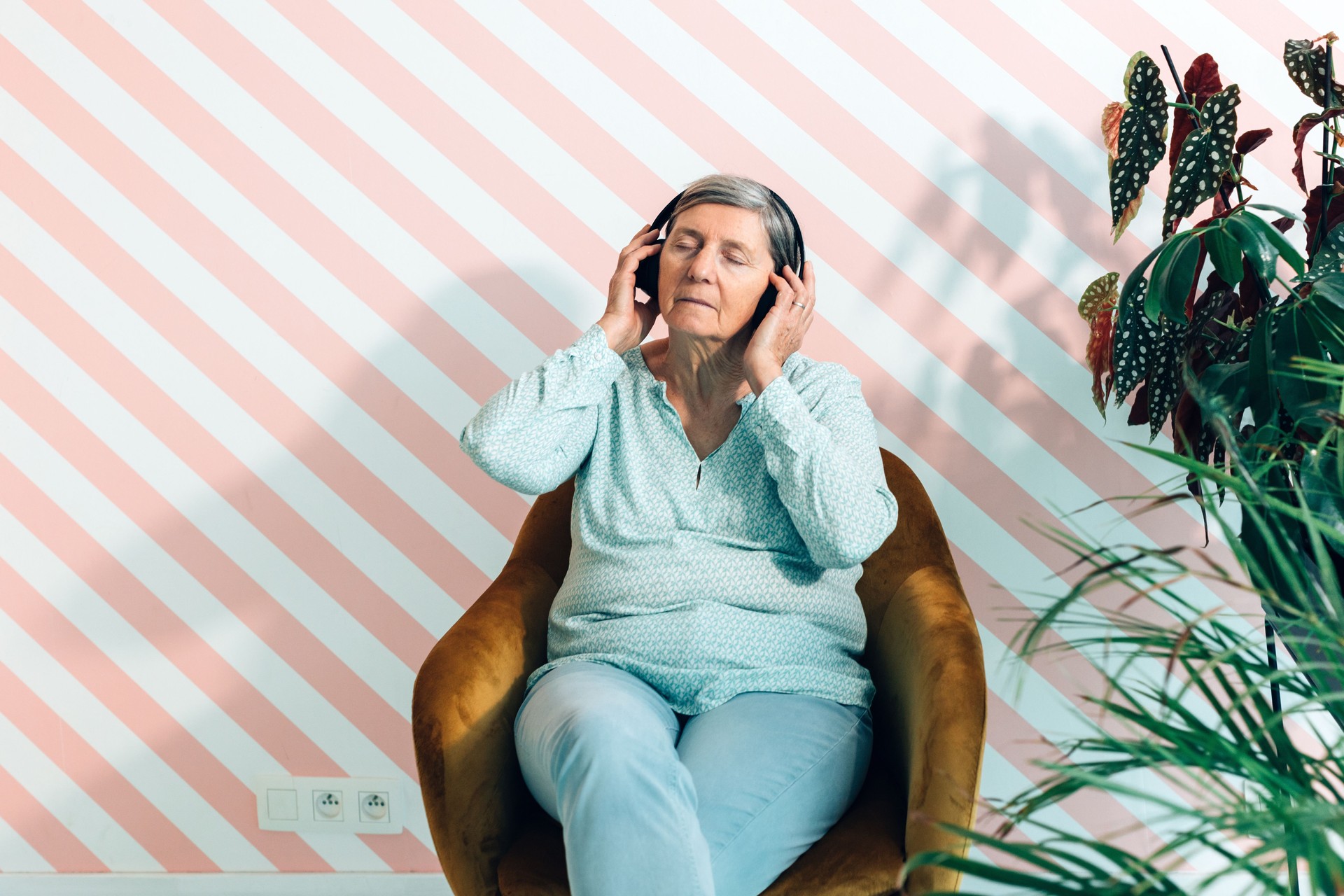 senior old lady sitting in comfortable chair listen to music with headphone